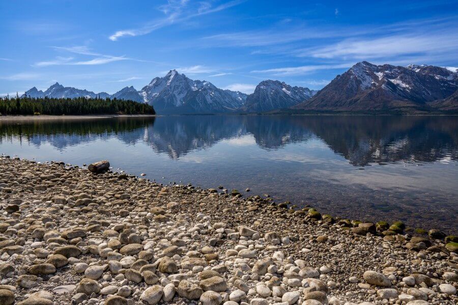 Stones on a lakeside beach with mountains reflecting in water