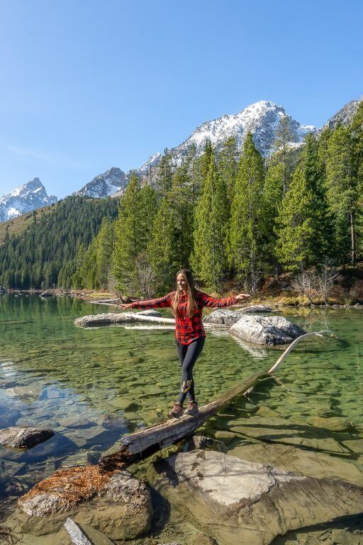 Kristen walking across a log in a lake in Wyoming