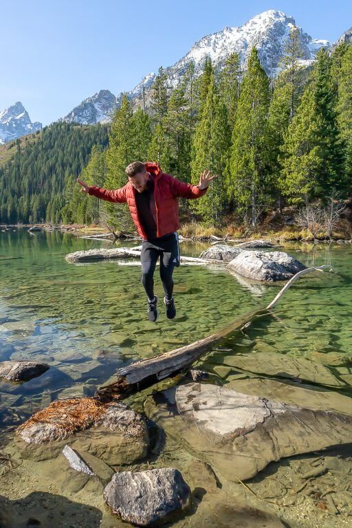 Mark jumping on a log in a clear lake in Wyoming