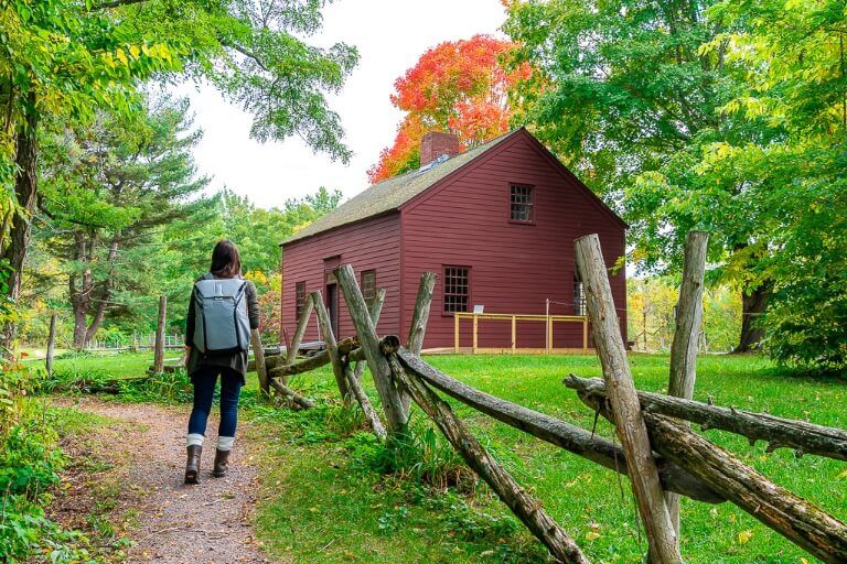 Kristen walking on a path through lush green farm with barn and red trees