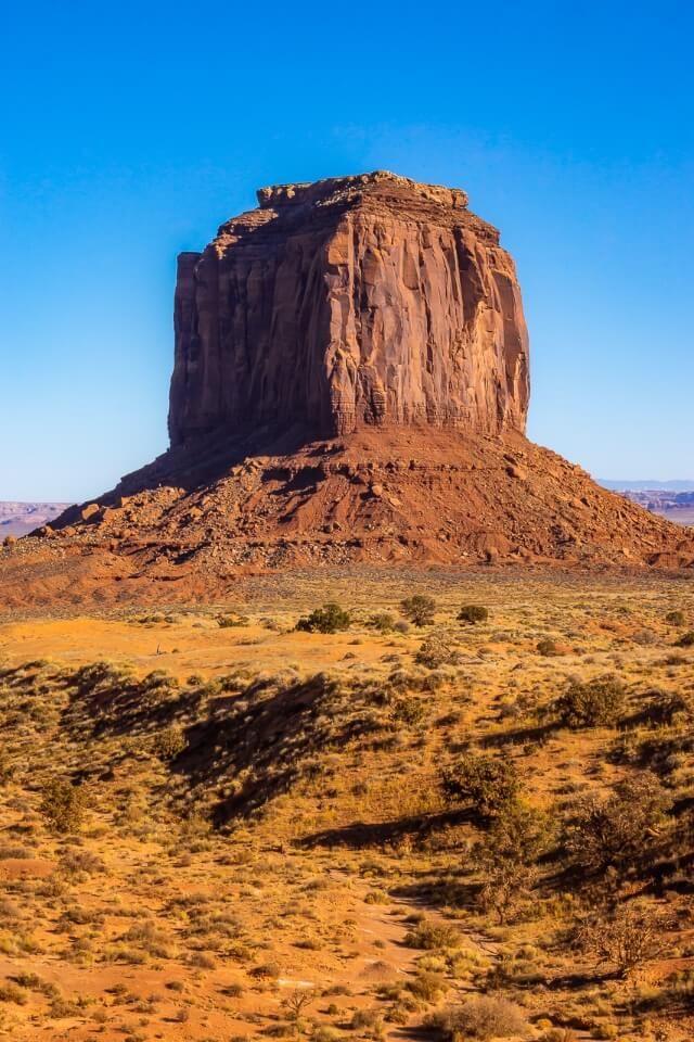 Single butte protruding out of the arizona desert at monument valley