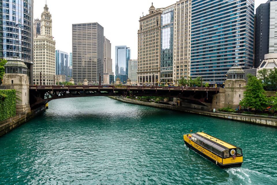 Turquoise river in chicago with yellow boat and skyscrapers