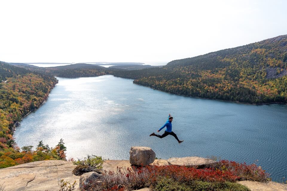 Mark jumping between rocks perspective against lake at acadia national park maine usa