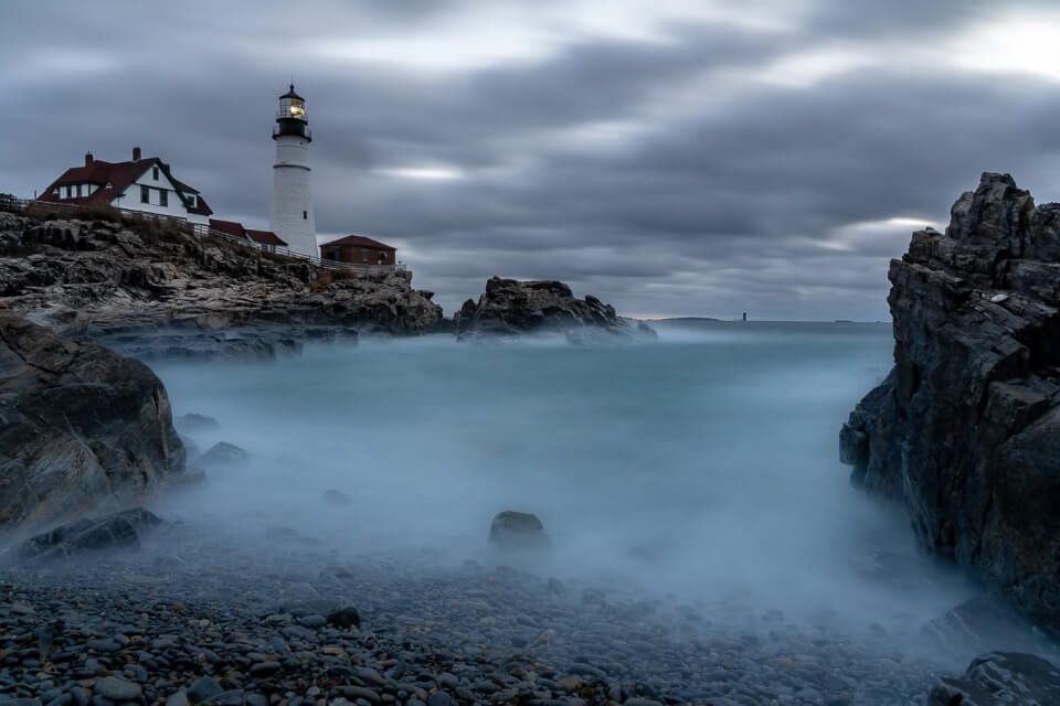 Sunrise at portland head lighthouse with long exposure on water creating cloudy effect maine photography