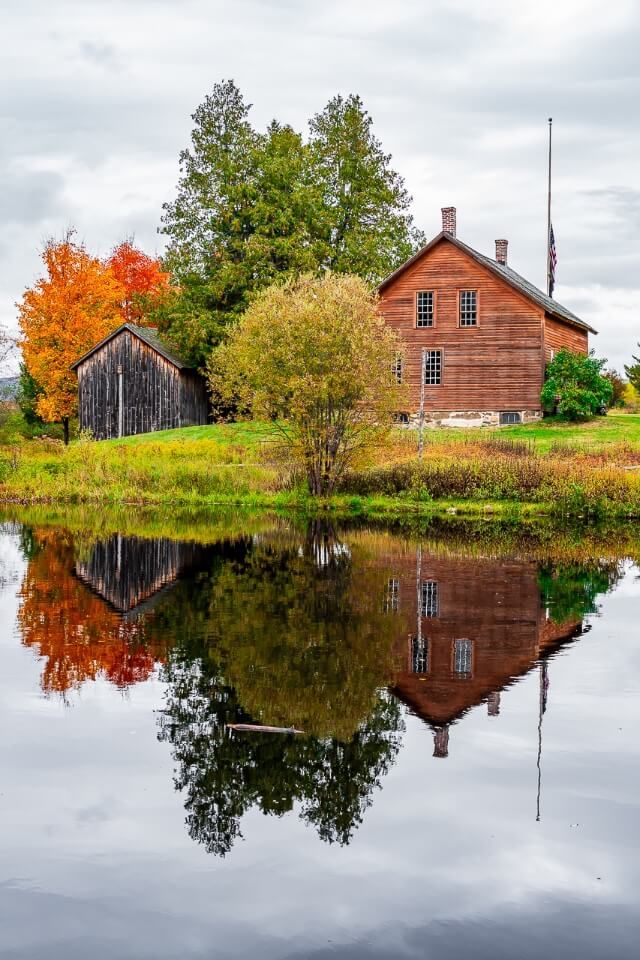 Wooden house barn and trees reflecting perfectly in a small lake museum near ski jump in lake placid new york adirondacks photography