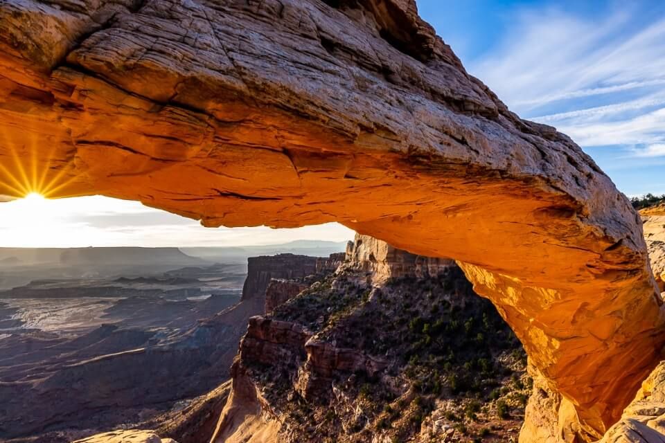 Mesa Arch canyonlands is one of the most iconic sunrise pictures in america underneath of arch illuminates red