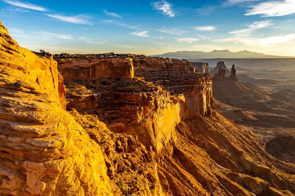 sunrise over stunning rock gorge in canyonlands national park utah usa rock face lit up by sun and blue sky