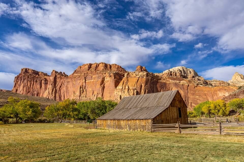 Capitol Reef national park in utah america has a stunning picture of fruita barn with orange rocks behind