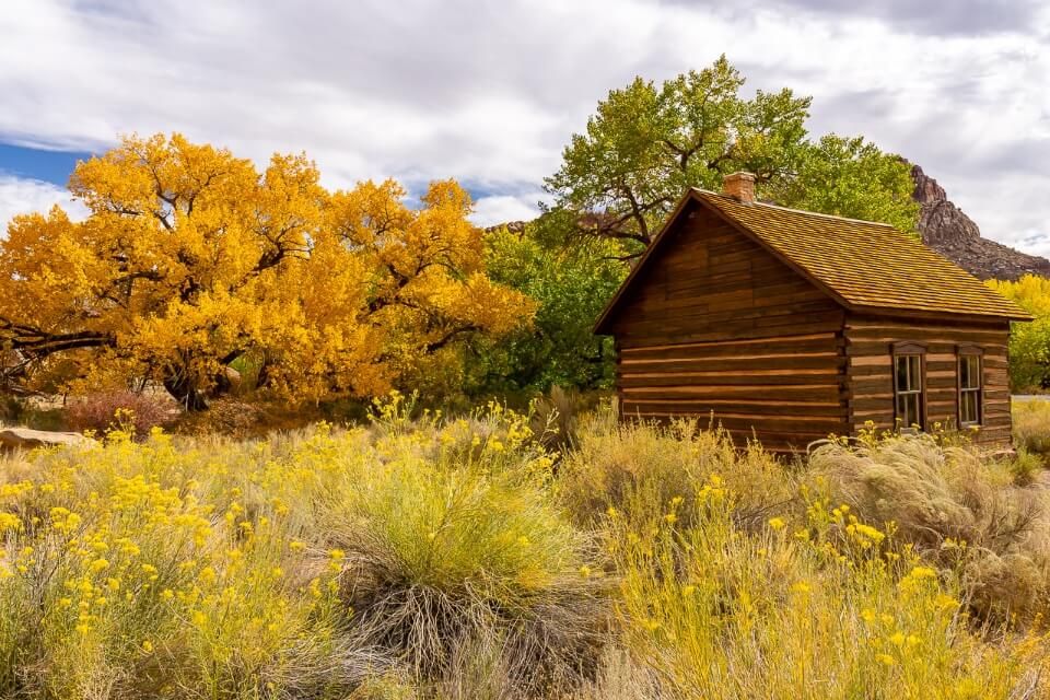 Fruita schoolhouse tiny wooden building surrounded by stunning fall foliage colors in capitol reef national park utah usa
