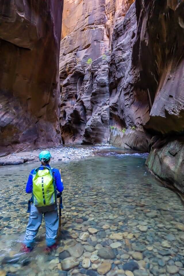 Kristen in full waterproof gear in the virgin river hiking the narrows trail at zion national park utah usa