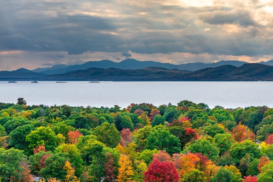 Amazing fall foliage trees lake mountains and sky picture of burlington vermont america with sun rays shining through clouds stunning image