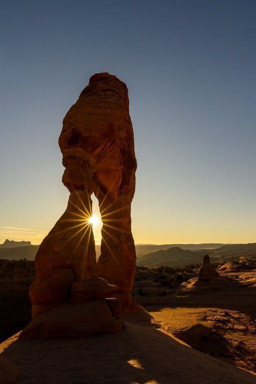 Delicate Arch starburst with the sunset looking incredible in utah arches national park after hiking to the summit