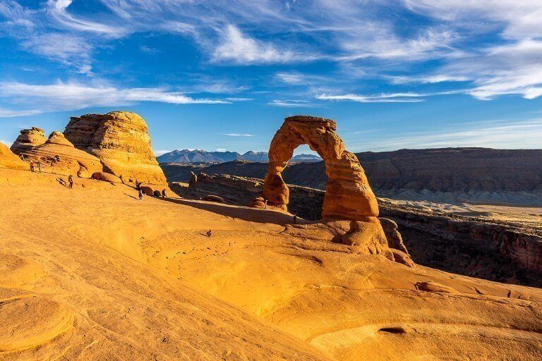First time you see Delicate Arch from the delicate arch hike just before sunset the orange rocks glowing and blue sky contrasting