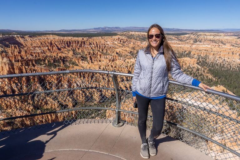 Kristen at Bryce point posing for a photograph in front of metal barrier