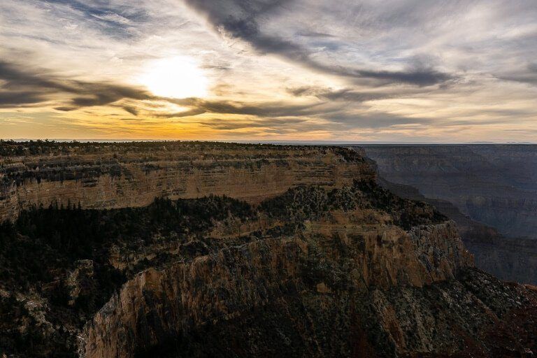 Sun setting over a cliff with sun behind clouds in arizona