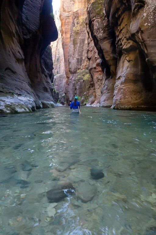 Kristen waist deep in the virgin river between canyon walls in utah