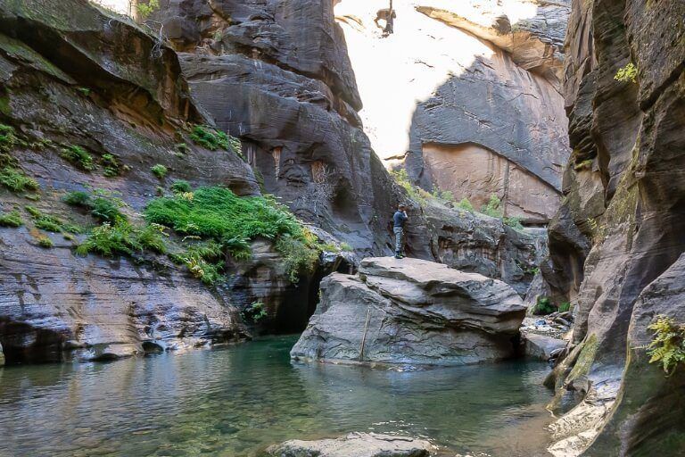 Mark climbing on a huge boulder to continue the hike further into the Narrows in zion national park utah