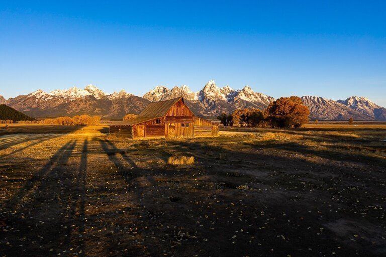 Field with wooden building and mountains