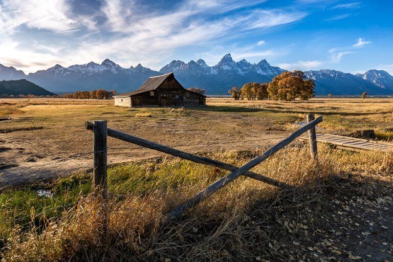 TA Moulton Barn on mormon row in grand teton national park at sunset behind a fence