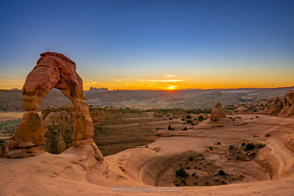 Stunning sunset at Delicate Arch in Arches national park deep blue sky with oranges and yellows on the horizon