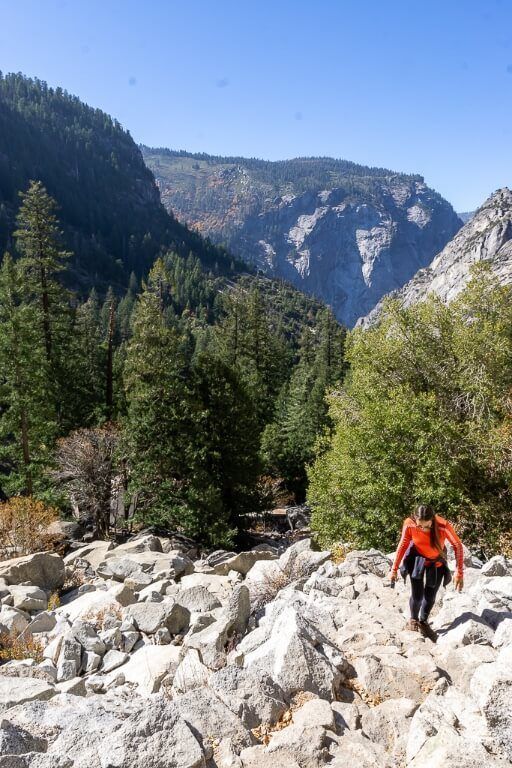 Kristen hiking up rocks on switchbacks with awesome valley behind