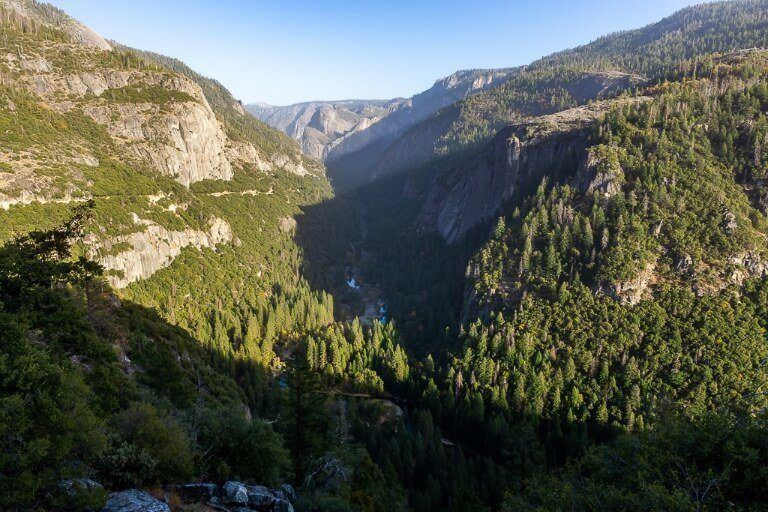 Big oak Flat road driving down a winding road into Yosemite Valley from Tioga Road huge wide open valley covered in trees and shadows