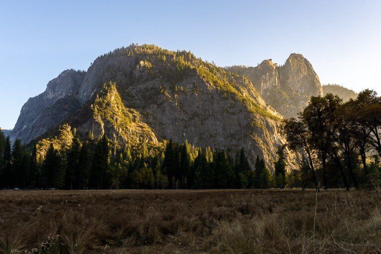 Sunset over looming granite dome with meadow in shadow foreground stunning yellows