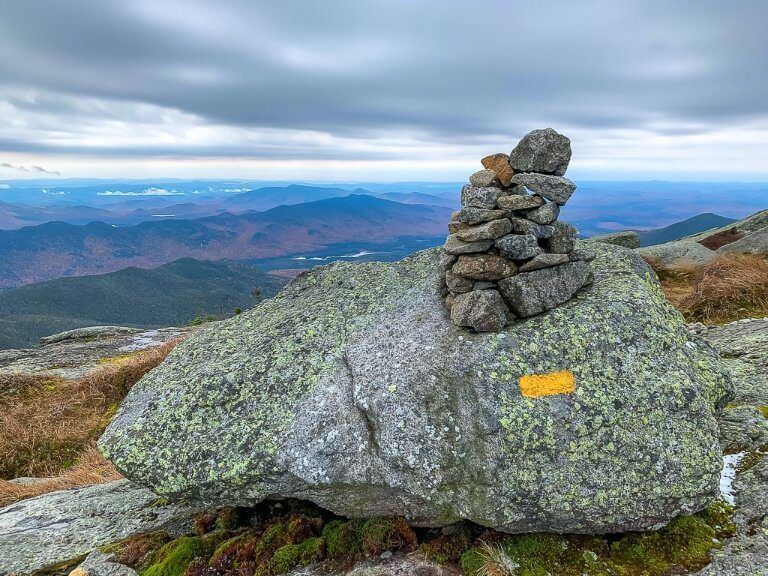 Cairns piles of rocks marking the trail to Mount Marcy summit and the highest point in new york with clouds and views of rolling hills