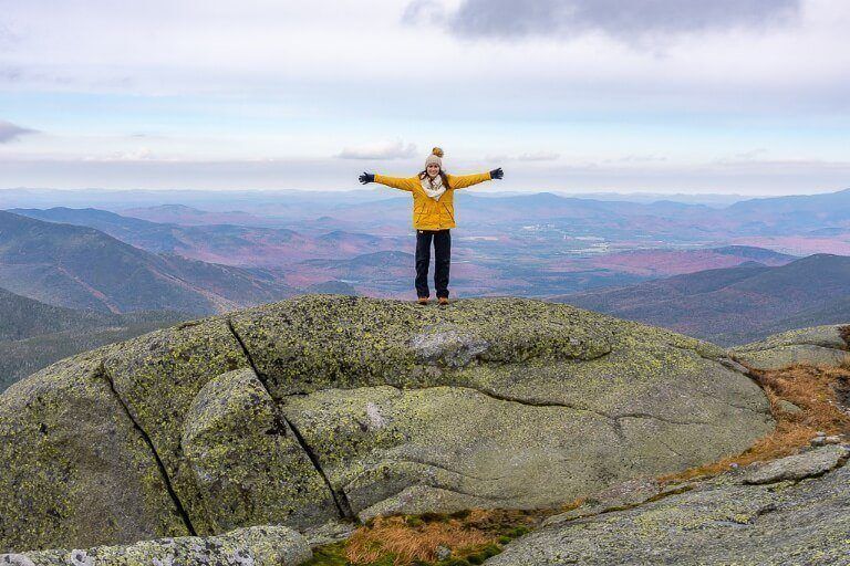Woman with arms outstretched celebrating reaching the highest point in new york mount marcy adirondack high peaks