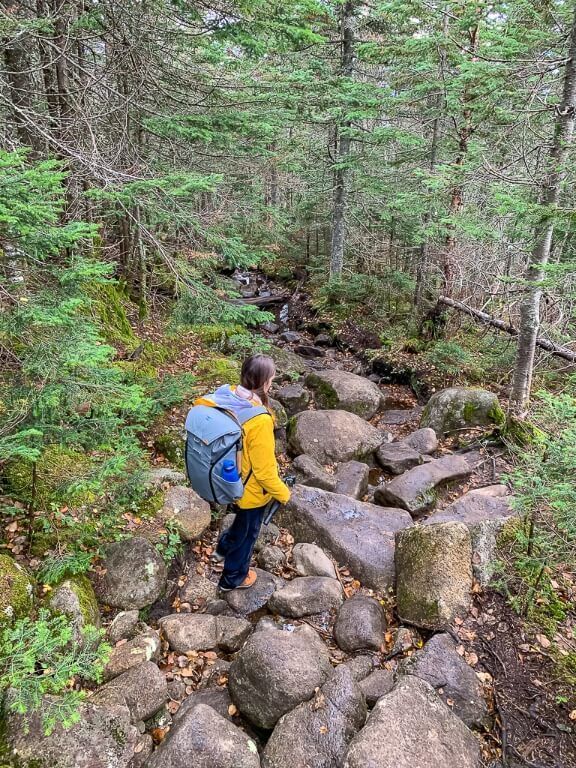 Woman walking on boulder trail hiking to the summit of mount marcy and the highest mountain in new york