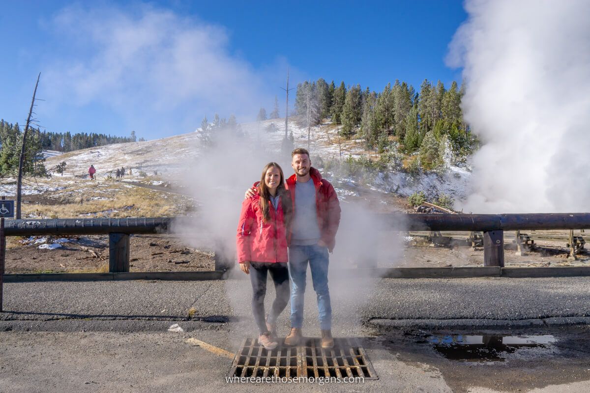 Mark and Kristen from Where Are Those Morgans stood on a grate with smoke billowing out in Yellowstone national park Wyoming