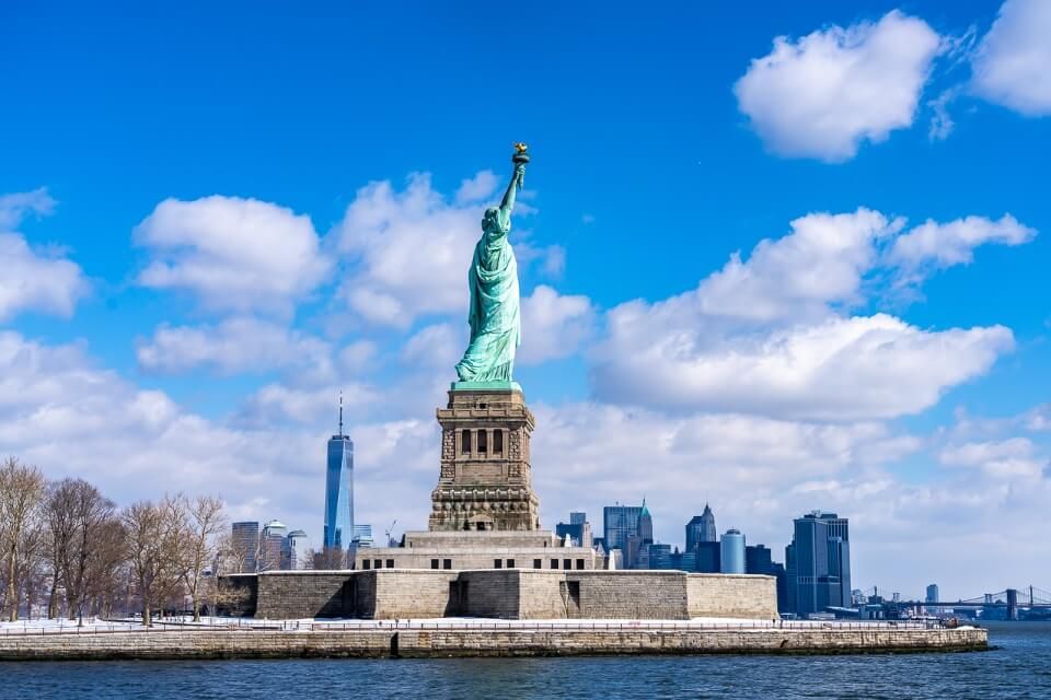 Lower Manhattan behind the statue of liberty from a ferry tour on the river Hudson