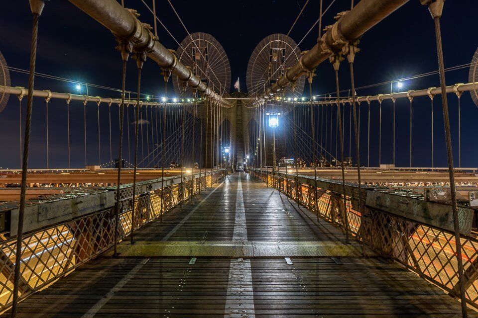 An empty pedestrian walkway along the Brooklyn Bridge at night