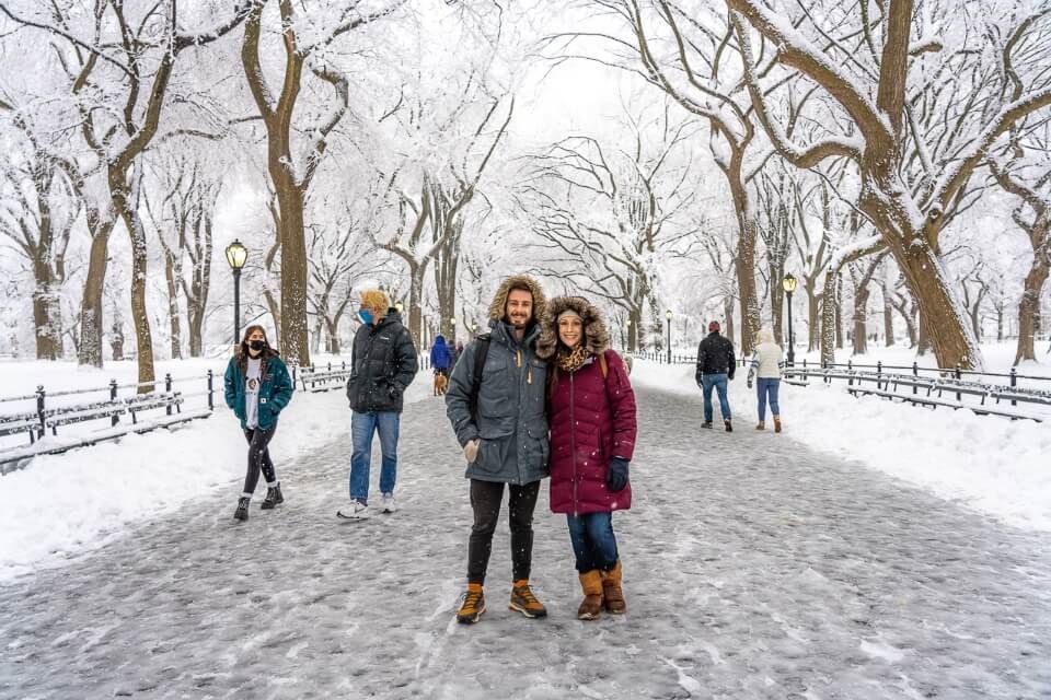 Man and woman taking a photo along the Mall in New York City on a snowy day in winter
