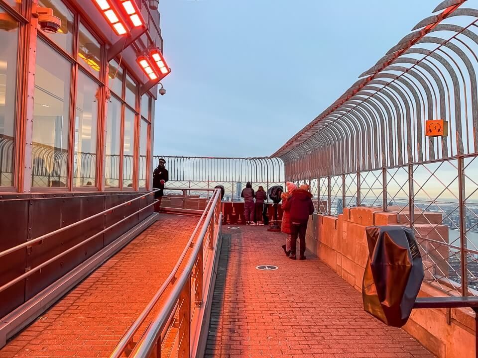 Empire State Building has a mesh fence with diamond shaped holes on its observation deck and a red glow