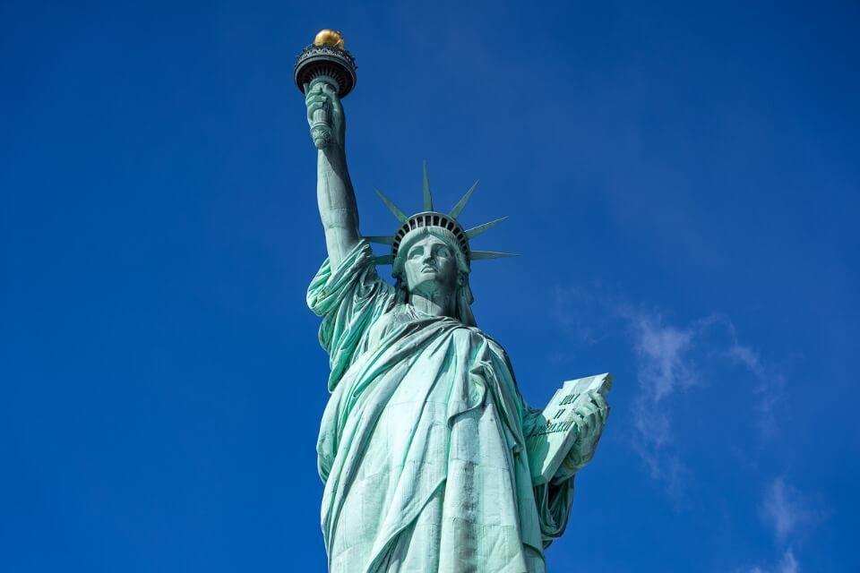 Statue of liberty is unmissable on a 4 days in new york city itinerary for first time visitors lady liberty holding torch high into the blue sky
