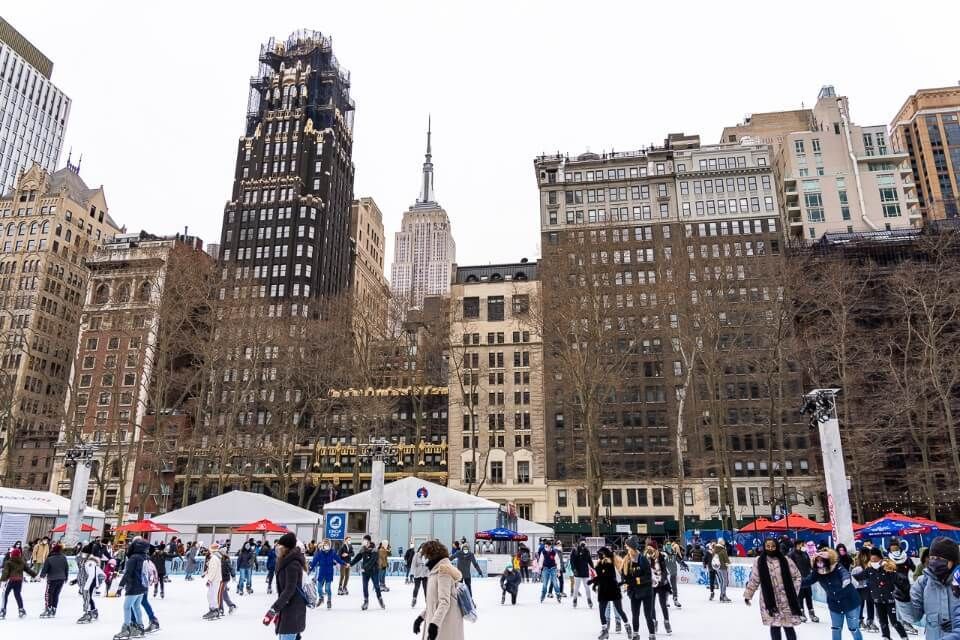Ice skaters in bryant park with empire state building in background
