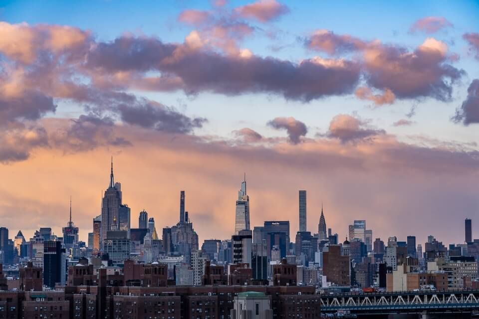 Midtown Manhattan famous buildings from Brooklyn Bridge during sunset with an incredible sky