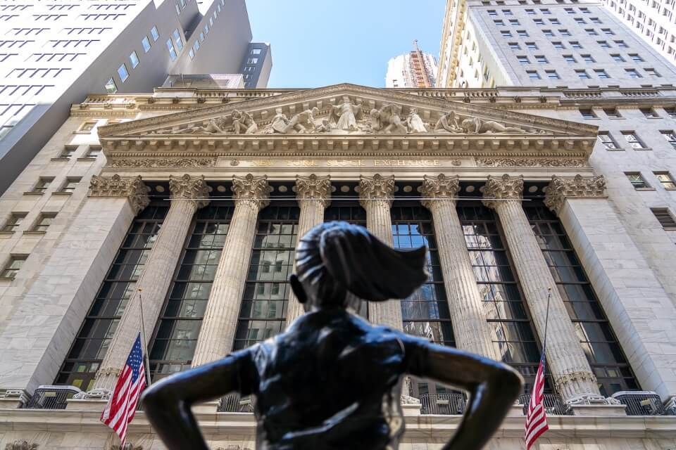Fearless girl statue looking up at NYSE in financial district lower manhattan