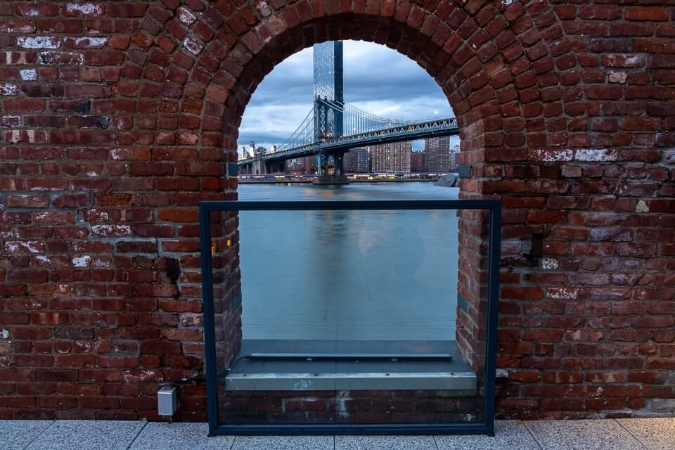 Hidden gem NYC photography location Manhattan Bridge through an arched brick window