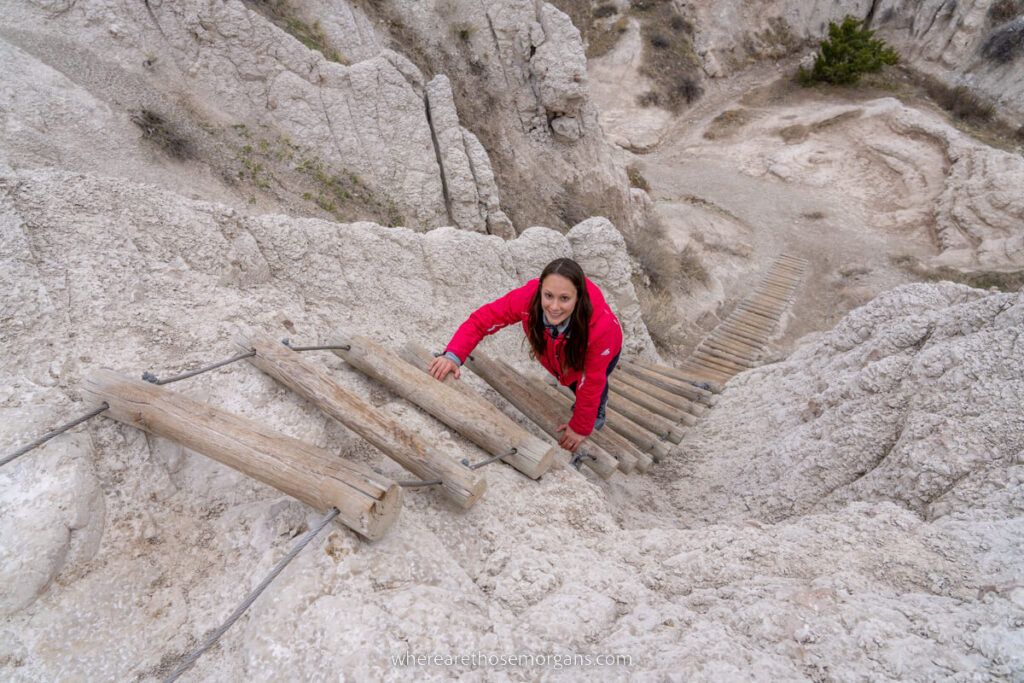 Woman climbing a wooden ladder on a granite rock landscape