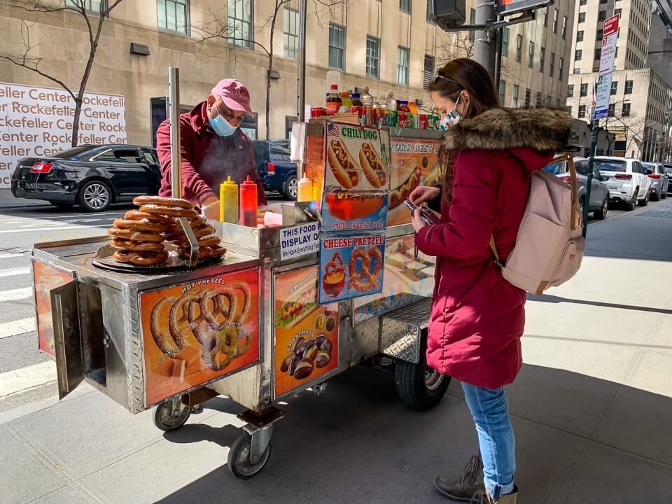 Buying a hotdog from a hotdog stand on fifth avenue in new york city