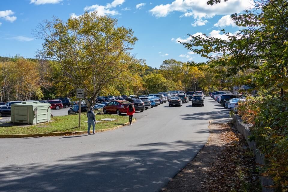 Parking lot filled with cars and people walking