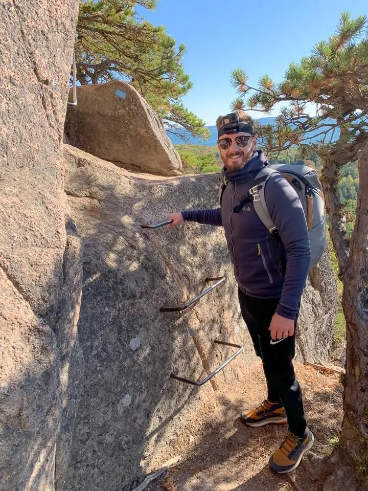 Hiker wearing action camera on head getting ready to climb up a metal ladder built into rocks