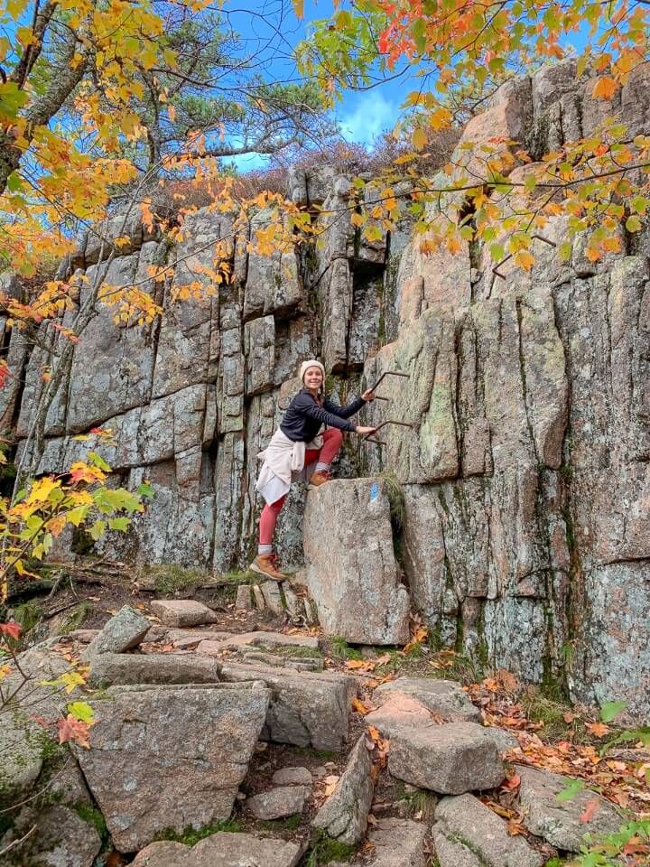 Woman climbing iron ladders on a stunning hike in maine