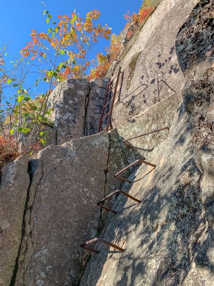 Ladders made of iron bars in rock on the side of precipice trail hike acadia
