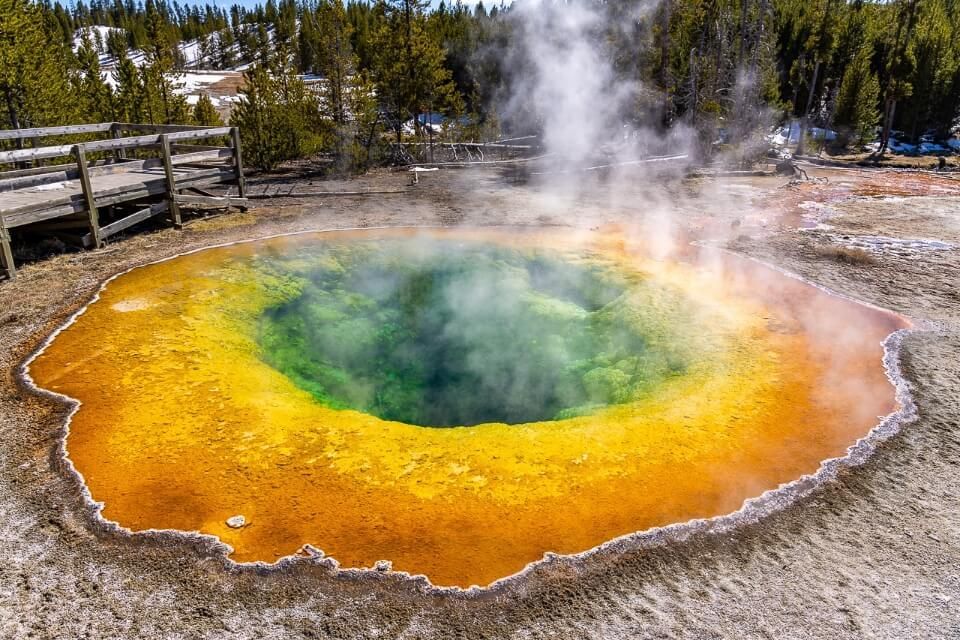 Best Things To Do In Yellowstone National Park Morning Glory Pool Stunning vibrant colors oranges yellows greens and blacks with steam billowing