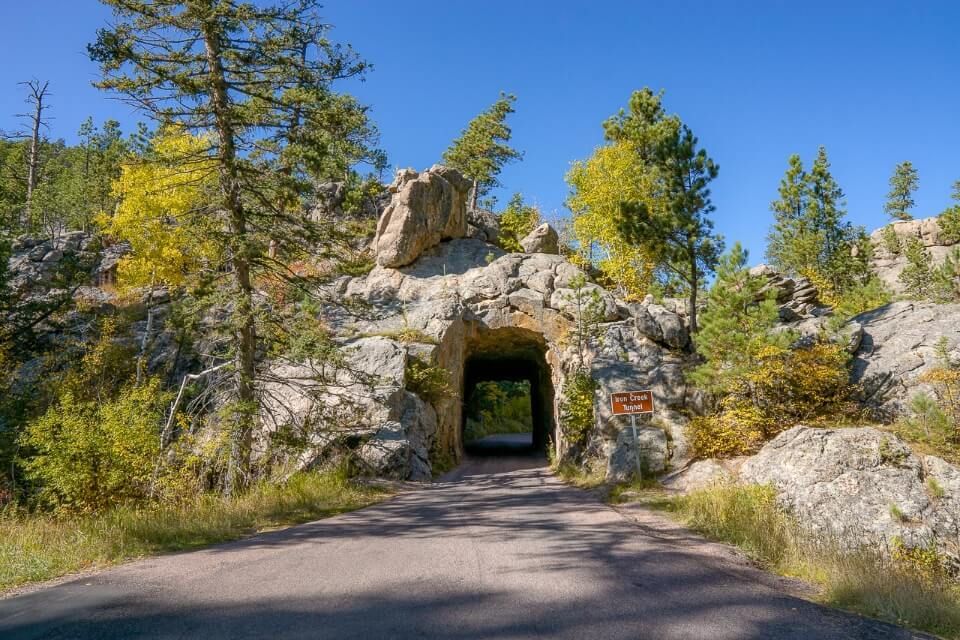 Narrow tunnel leading through granite rock on needles highway in south dakota is one of the most amazing drives near mt rushmore