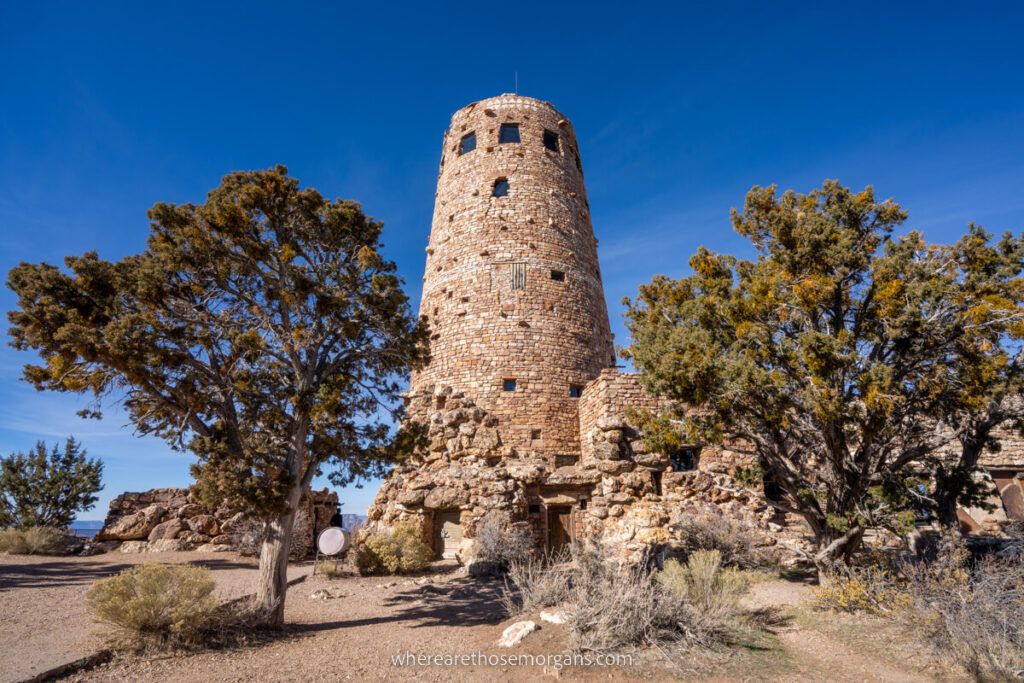 Desert View Watchtower on the far eastern side of Grand Canyon South Rim tall stone tower surrounded by trees on a sunny day with deep blue sky