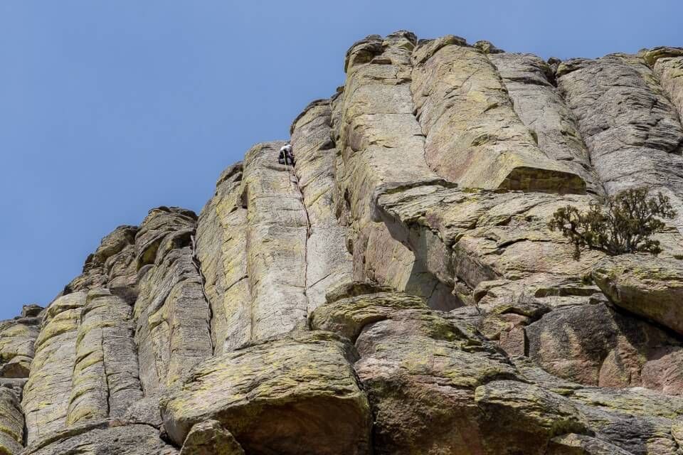 Man climbing on rock face with hexagonal shaped cracks